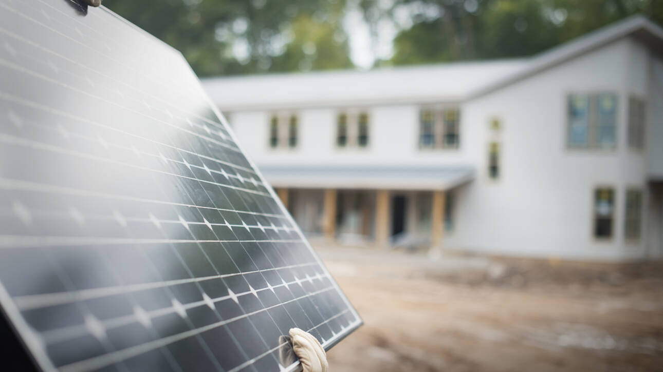 a workman carrying a large solar panel at a green 2025 04 04 07 10 23 utc