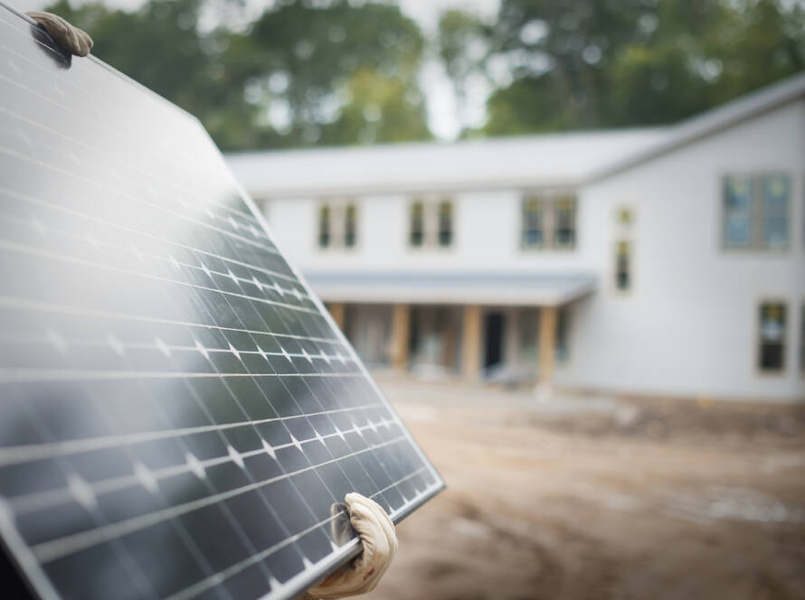a workman carrying a large solar panel at a green 2025 04 04 07 10 23 utc